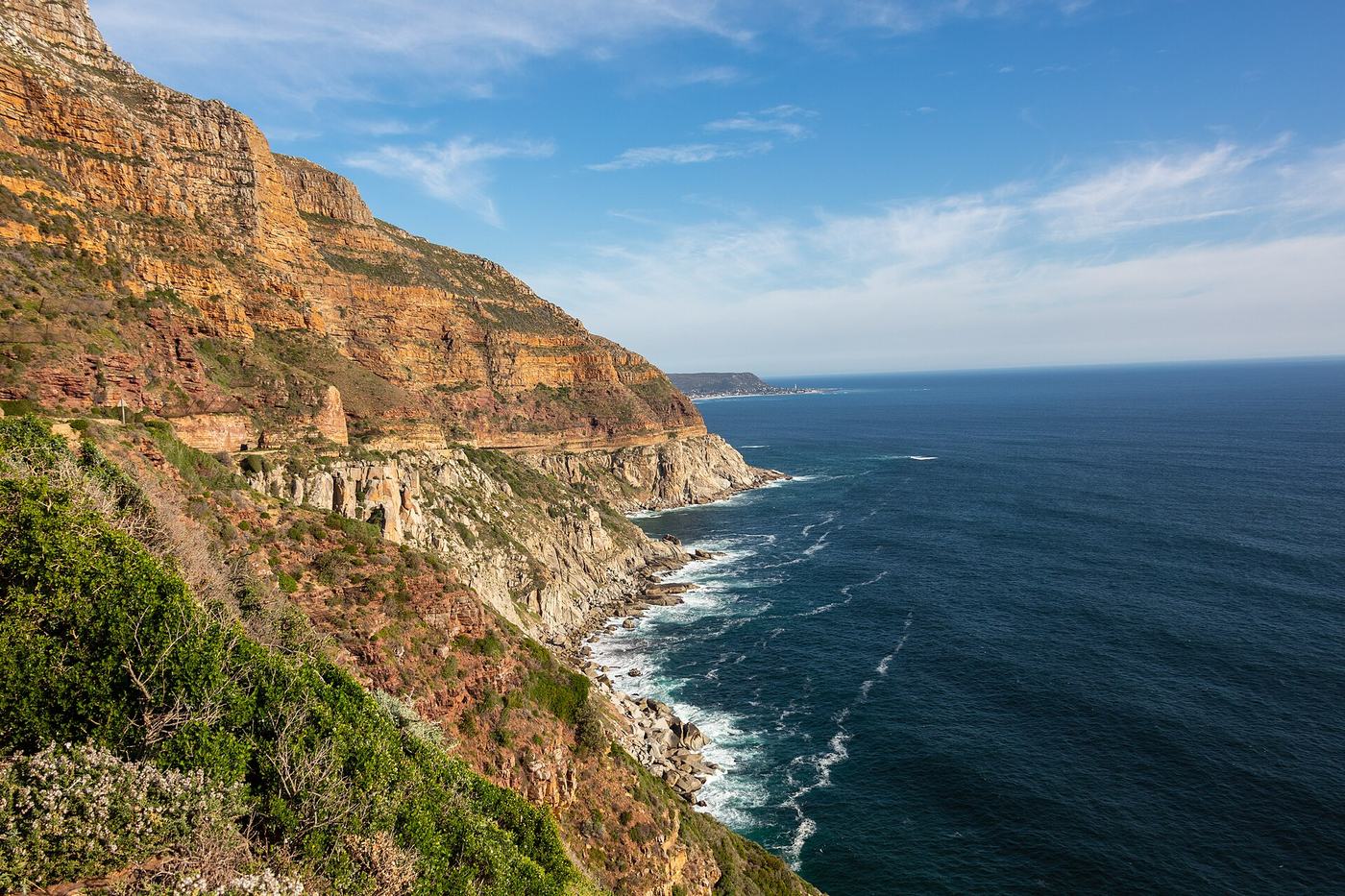 Steile, ockerfarbene Felswände fallen am Chapman's Peak Drive zum tiefblauen Atlantik ab